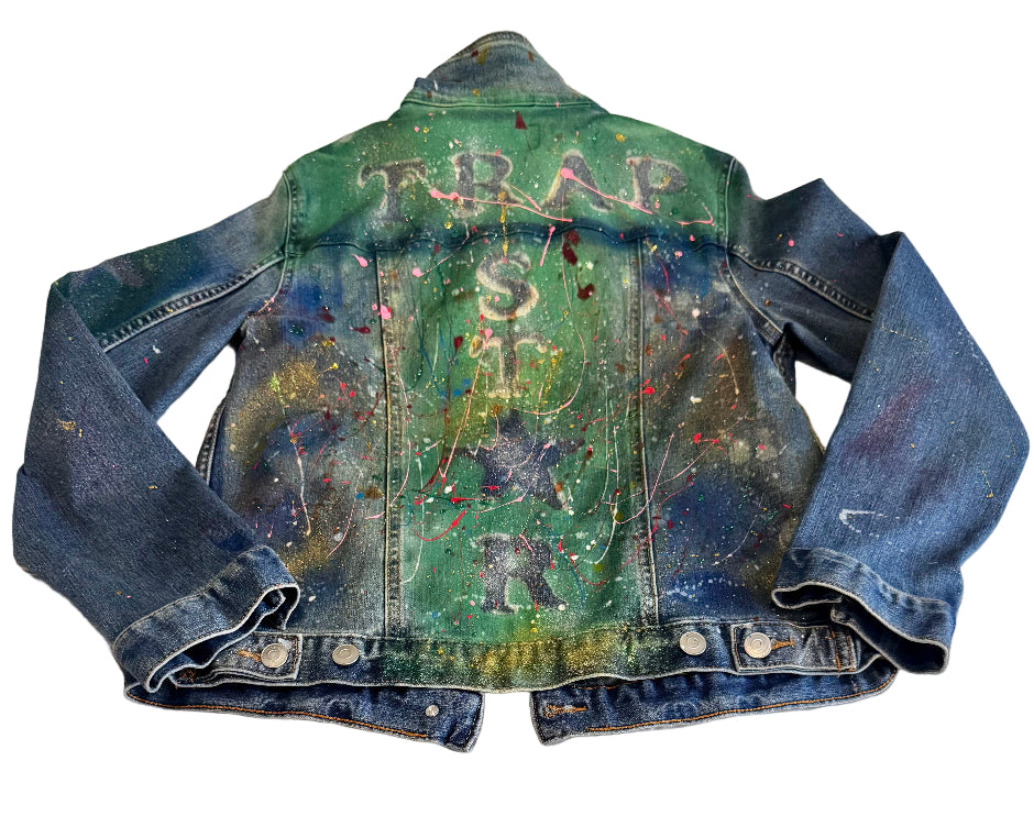 Denim jacket with artistic designs and text on a textured surface