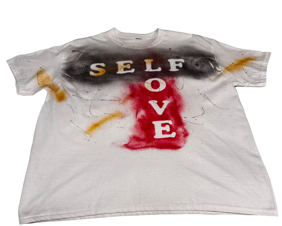 White t-shirt with spray paint text on a gray surface