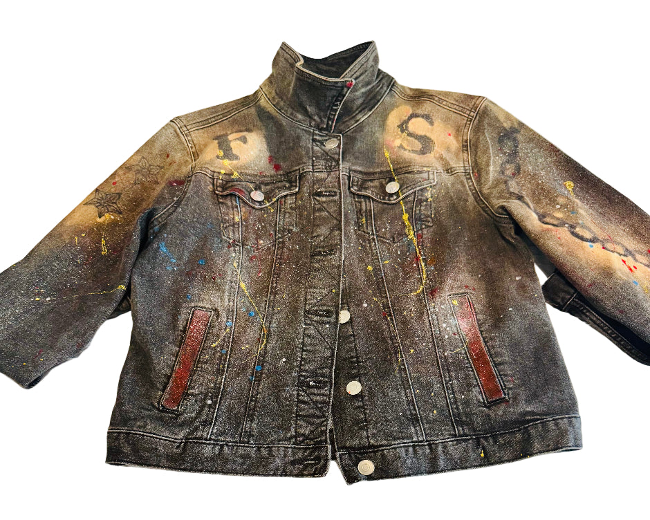 Denim jacket with paint splashes and stains on a textured surface