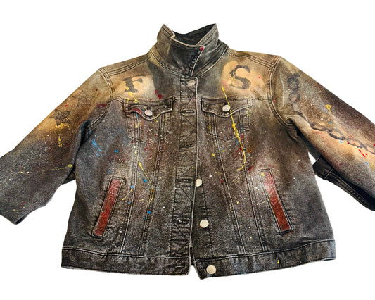 Denim jacket with paint splashes and stains on a textured surface