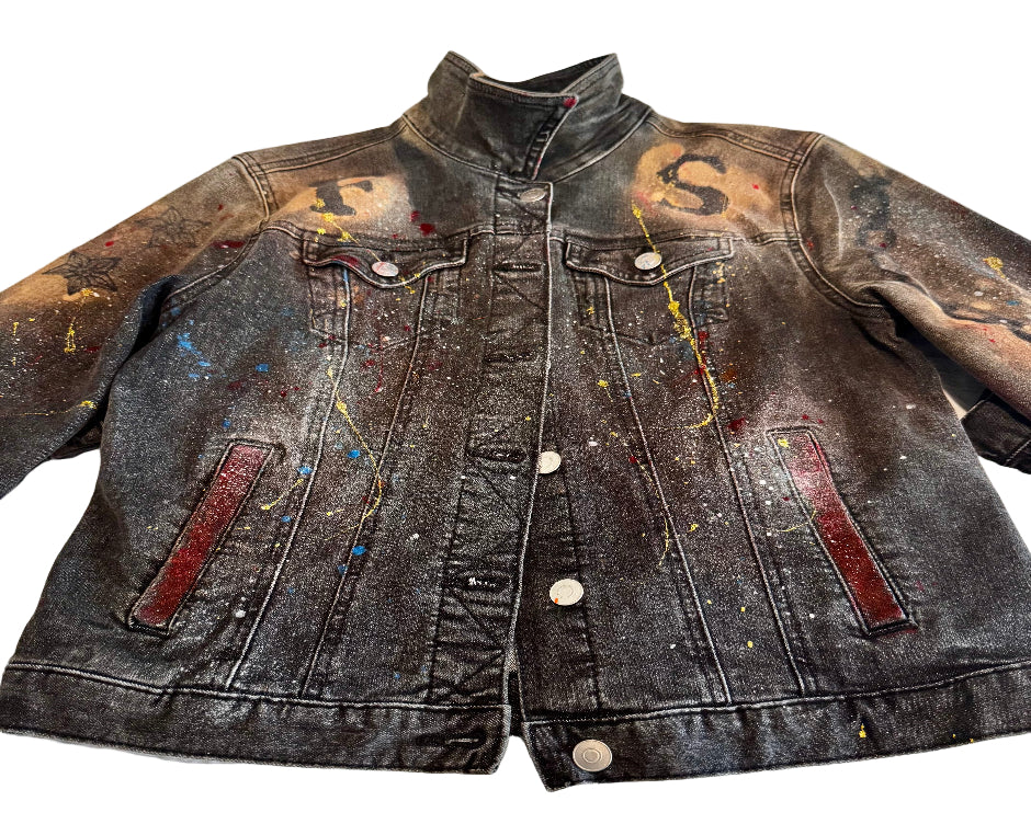 Denim jacket with paint splashes and designs on a textured surface