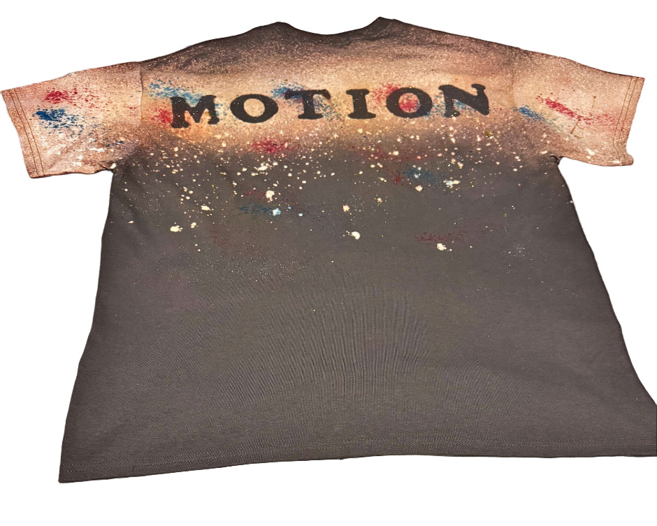 T-shirt with 'MOTION' printed on the back, laid flat on a bed.
