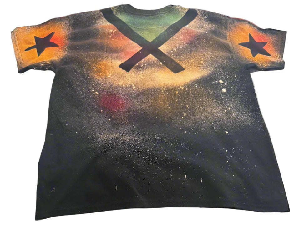 Black t-shirt with colorful spray paint design on a white bedspread