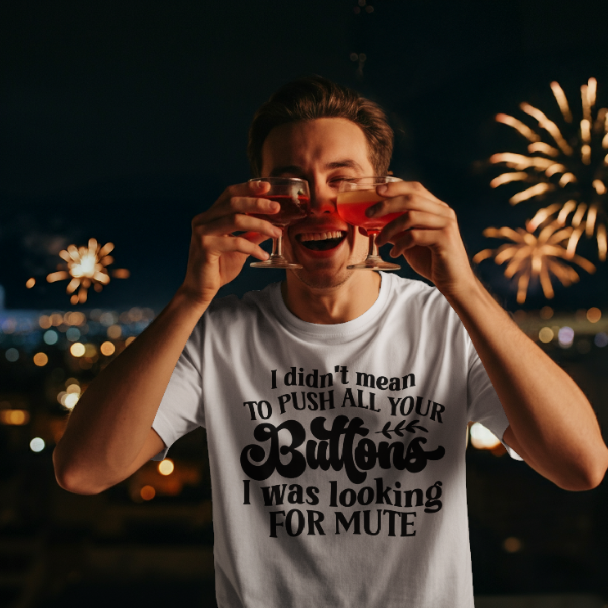 Person holding two drinks with fireworks in the background, wearing a t-shirt with text.