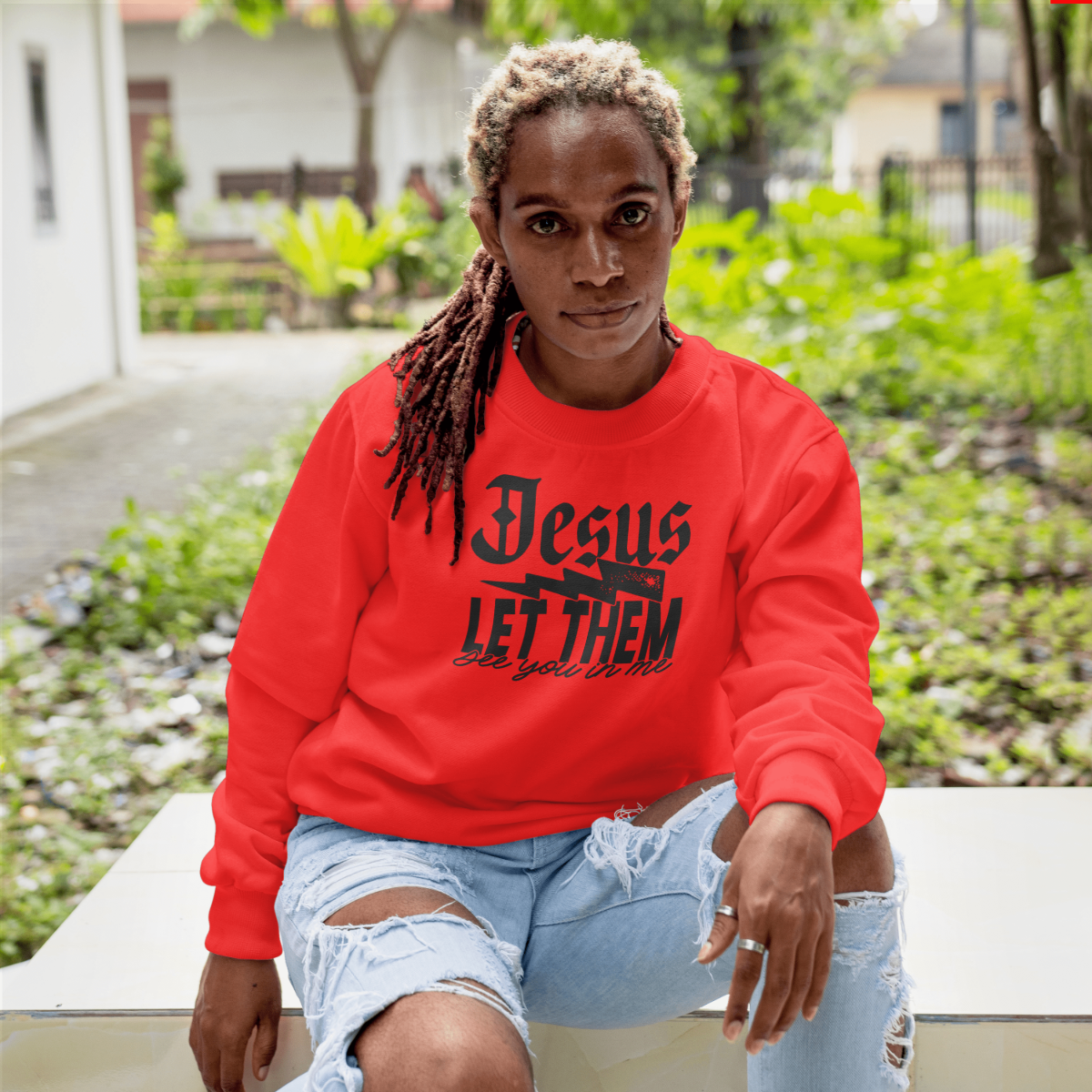 Person wearing a red sweatshirt with text, sitting outdoors.