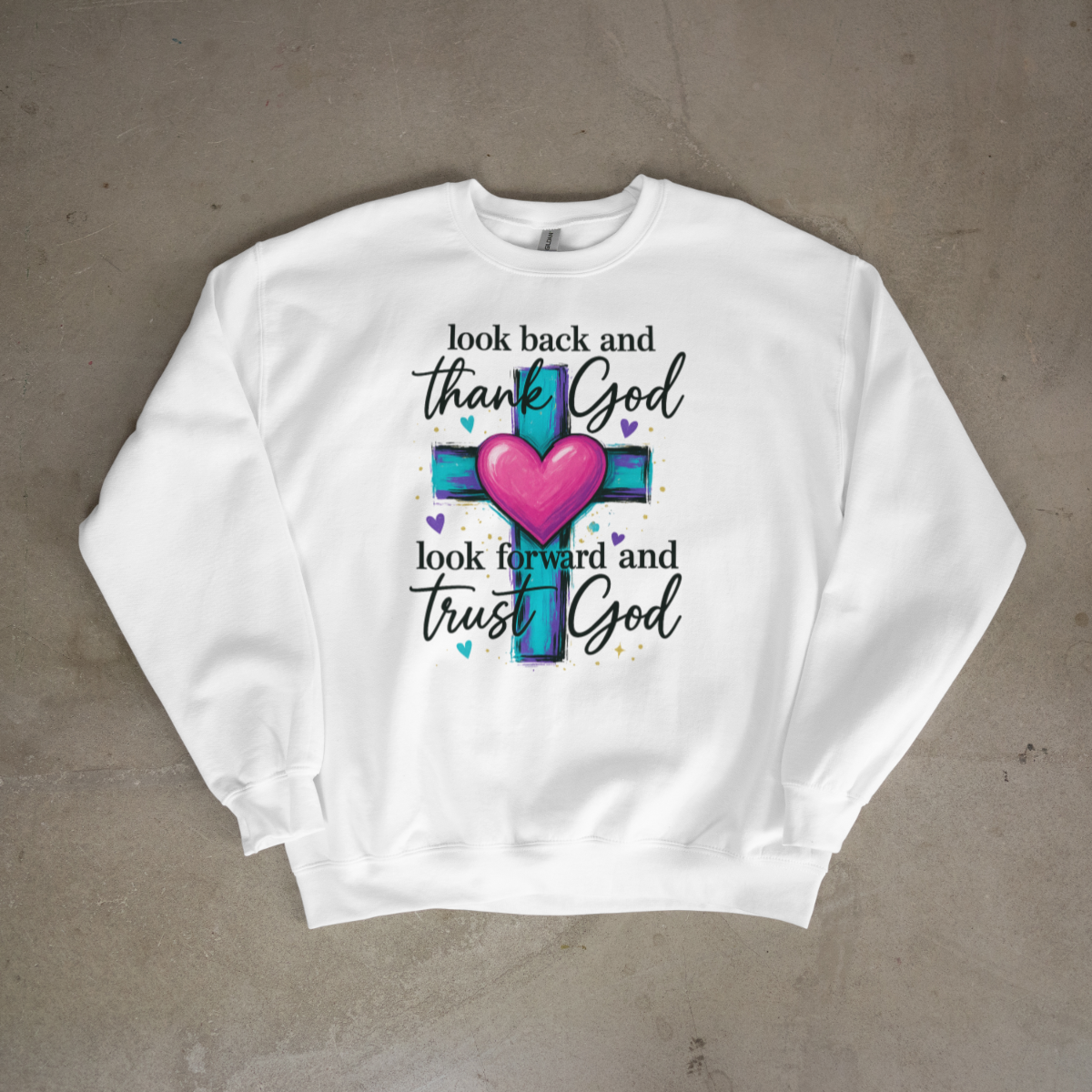 White sweatshirt with a colorful cross and heart design on a gray surface