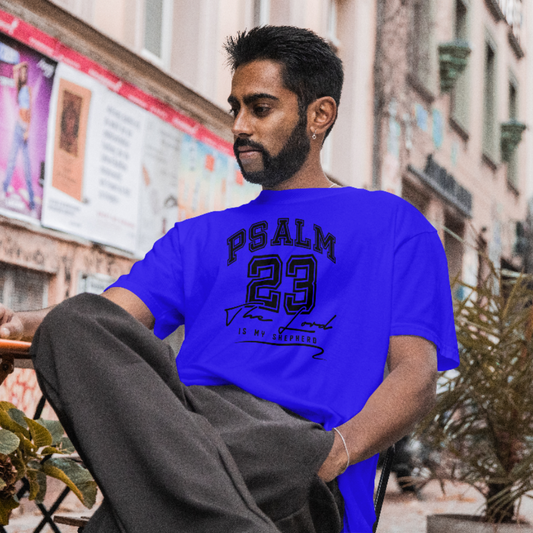 Man wearing a blue t-shirt with 'PSALM 23' text sitting on a bench in an urban setting.
