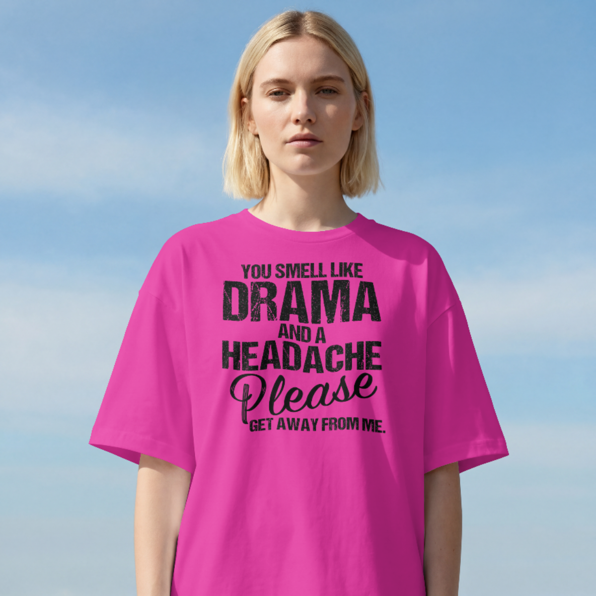 Person wearing a pink t-shirt with text against a clear blue sky