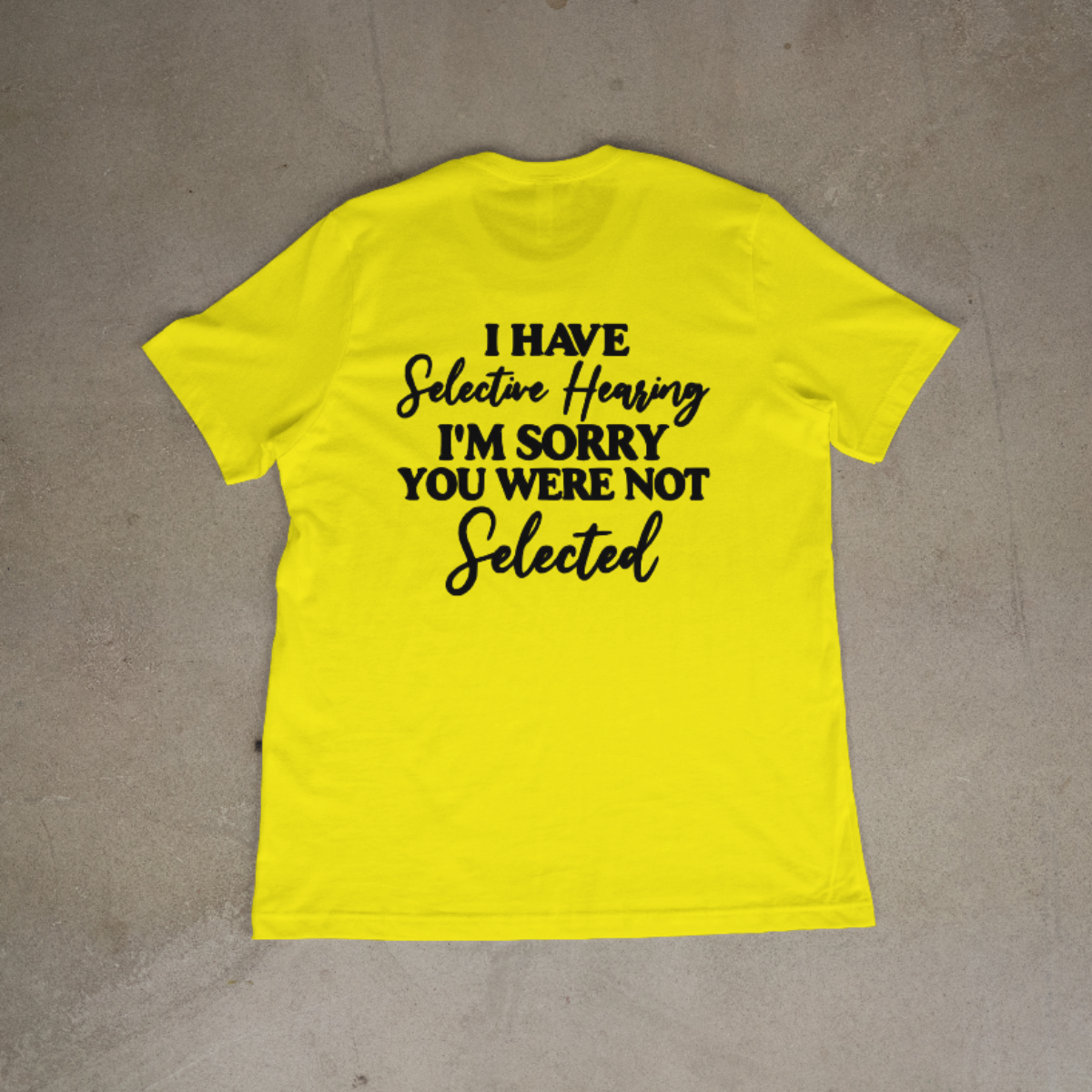 Yellow t-shirt with black text on a gray surface