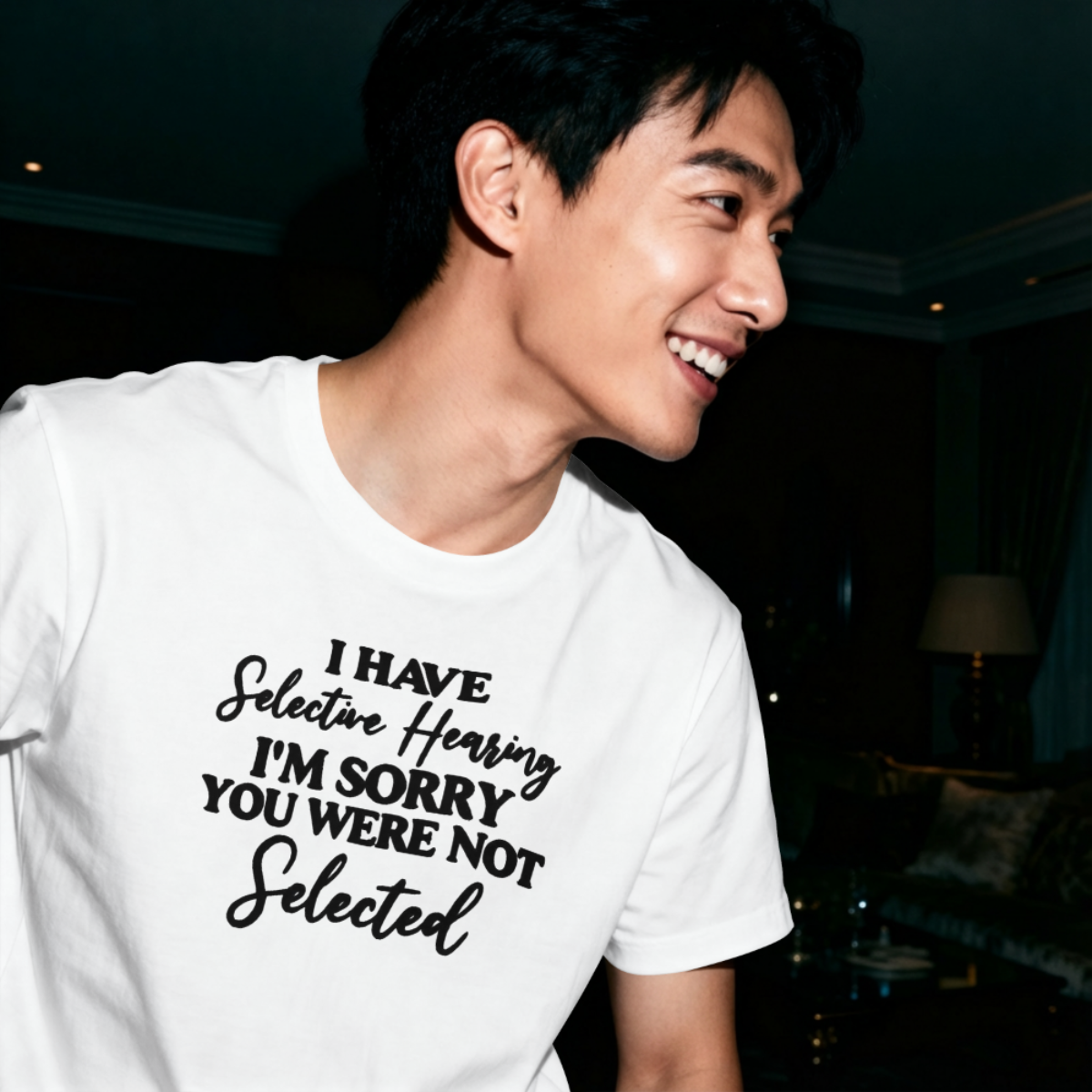 Person wearing a white t-shirt with humorous text in a dimly lit room.