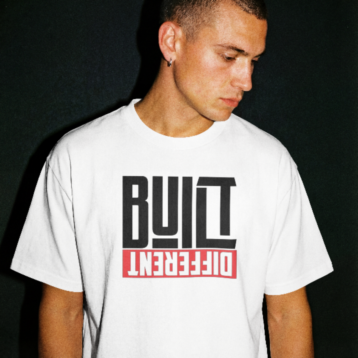 Man wearing a white t-shirt with 'Built Different' text design on a black background