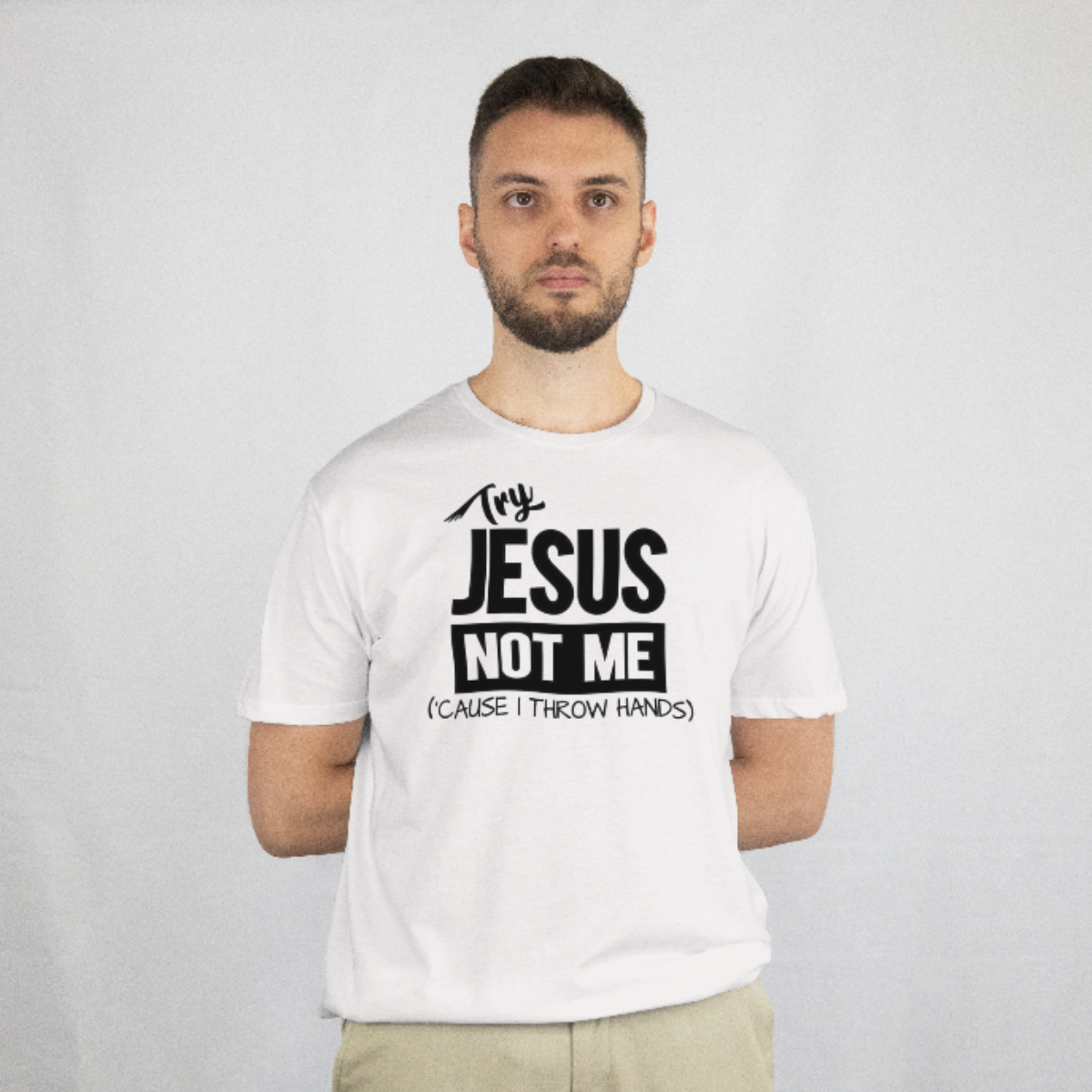 Man wearing a white t-shirt with text 'Try  JESUS NOT ME (cause I throw hands)' on a plain background