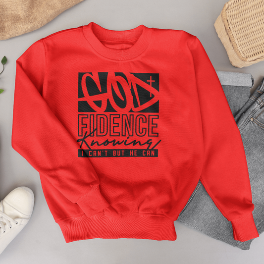 Red sweatshirt with black text design on a gray surface with shoes and jeans.