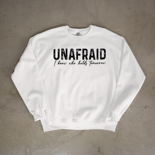 White sweatshirt with 'UNAFRAID I know who holds tomorrow' text on a gray background