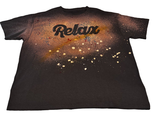 Black t-shirt with 'Relax' text and spray paint effects on a textured surface