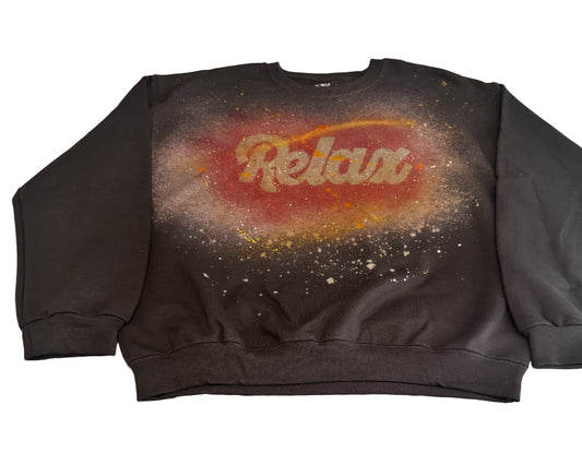 Black sweatshirt with 'Relax' graphic on a textured surface