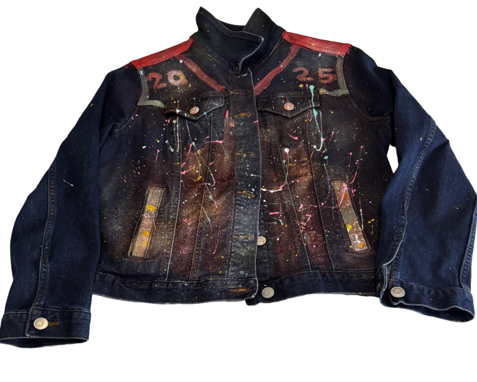 Denim jacket with splatter paint design on a light wooden surface